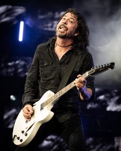 a man with long hair playing an electric guitar