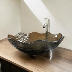 a glass bowl sink sitting on top of a wooden counter next to a faucet