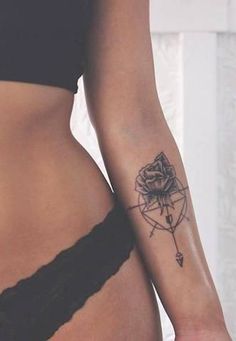 a woman's stomach with a rose tattoo on her left side and an arrow in the middle