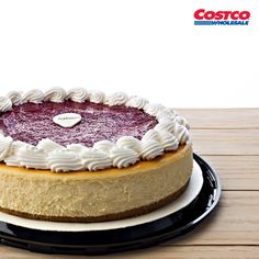 a cheesecake on a black plate with white frosting and a heart shaped decoration