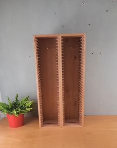 two wooden shelves sitting on top of a table next to a potted green plant