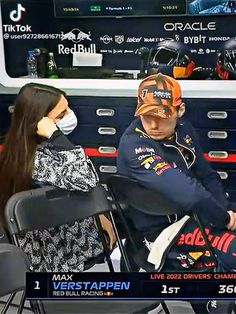 a man and woman sitting next to each other in front of a tv screen wearing masks