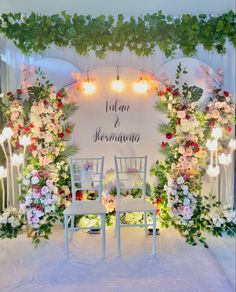 an outdoor wedding ceremony setup with flowers and greenery on the back wall, surrounded by white chairs