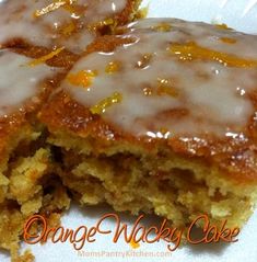 two pieces of cake on a plate with icing and oranges in the background