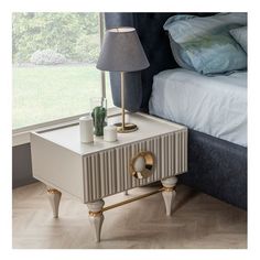 a nightstand with a lamp on it next to a bed