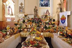 a table filled with lots of food in front of a stained glass window next to a statue