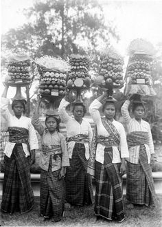 an old black and white photo of women carrying baskets on their heads