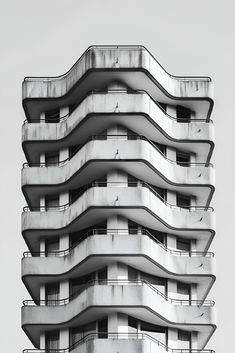 a tall building with balconies on the top and bottom floors in black and white