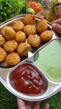 a person holding a tray with some food on it and dipping sauce in the other hand