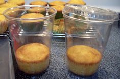 some cupcakes are sitting in plastic cups on a counter top next to other muffins