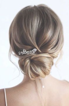 a woman with her hair pinned in a low bun and wearing a crystal brooch