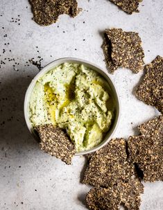 a bowl filled with hummus next to crackers