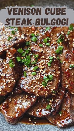 a plate filled with steak covered in sesame seeds and garnished with green onions