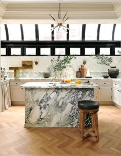 a kitchen with marble counter tops and stools next to an island in the middle