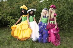 three women dressed up in costume posing for the camera with trees in the back ground