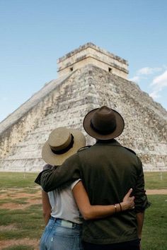 two people standing in front of an ancient pyramid with their arms around each other's shoulders