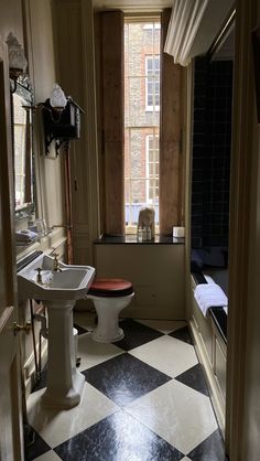 a bathroom with black and white checkered flooring next to a sink, toilet and window