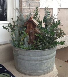 a potted plant with a birdhouse in it sitting on the front porch next to a window