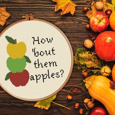 a cross - stitch pattern with the words how about them apples? surrounded by autumn leaves, acorns and gourds