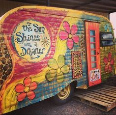 the sun shines on a dancer trailer is painted with flowers and words, as well as an orange door