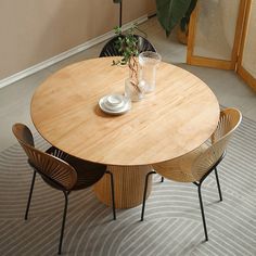 a round wooden table with four chairs around it and a potted plant on top