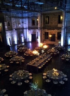 a large room with tables and chairs set up for an event at night, lit by candles