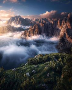 the mountains are covered in fog and clouds as they rise into the sky above them