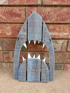 a wooden shark shaped object sitting next to a brick wall