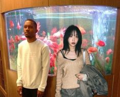 two people standing in front of a fish tank