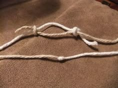 a piece of rope that is on top of a brown carpeted floor, with one knot tied to the end