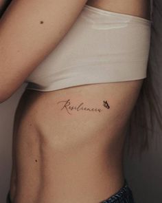 a woman with a small tattoo on her stomach and the word remembrance written in cursive writing