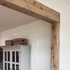 a white cabinet with baskets on top of it in a room that is painted white