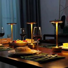 a table set with wine glasses, bread and fruit