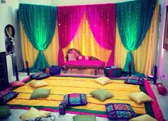 a room decorated in bright colors with pillows on the floor and drapes hanging from the ceiling