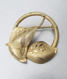 This very pretty 1940s late Art Deco period brooch is signed BB for Binder Brothers and 12k GF for gold filled.  It is a circle design with three textured overlaid leaves.  It measures 1.25 inches across and is in excellent condition with no signs of any wear or damage.    FREE SHIPPING within the USA and it will arrive gift boxed.    072 Vintage Yellow Gold Brooch For Anniversary, Gold Art Deco Brooches For Anniversary, Gold Art Deco Brooches As A Gift, Gold Art Deco Anniversary Brooches, Art Deco Gold Brooches As Gift, Vintage Brass Formal Brooches, Vintage Gold Round Brooches, Mid-century Gold Brooch Jewelry, Mid-century Gold Brooches For Vintage Events