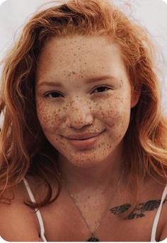 a young woman with freckles on her face and chest smiling at the camera