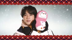 a young man holding a stuffed animal in front of a snow covered background with an ornament