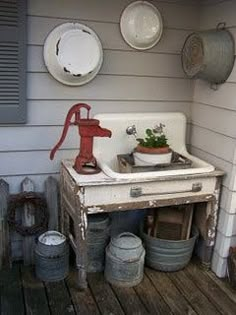 an old kitchen sink sitting on top of a wooden floor next to pots and pans