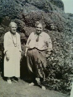 an old photo of two people standing next to each other