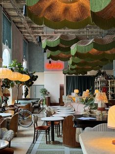 the interior of a restaurant with tables, chairs and umbrellas hanging from the ceiling