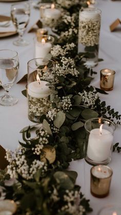 a long table with candles, flowers and greenery is set up for a formal dinner