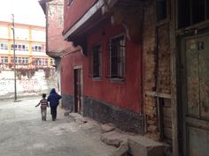 two people walking down an alleyway between buildings