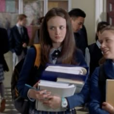 two girls in school uniforms are holding books