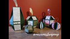 three small boxes are sitting next to each other on a table, one is made out of paper and the other has an ornament