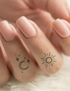 a person's hand with tattoos on it and the fingers that have sun and moon designs on them