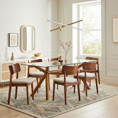 a dining room table with six chairs and a rug on the floor in front of it