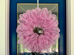 a pink mesh wreath hanging on the front door of a house with blue glass doors