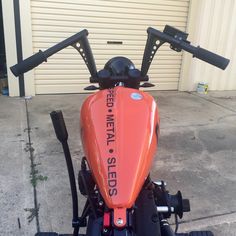 an orange motorcycle parked in front of a garage