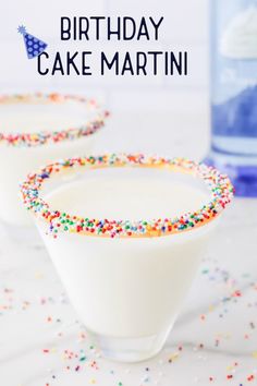 two glasses filled with white frosting and sprinkles next to a bottle of birthday cake martini