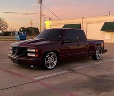 a maroon pick up truck parked in a parking lot next to a gas station building